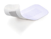 Single Cosmopor E extra-large sterile adhesive pad with cotton centre, shown for scale.
